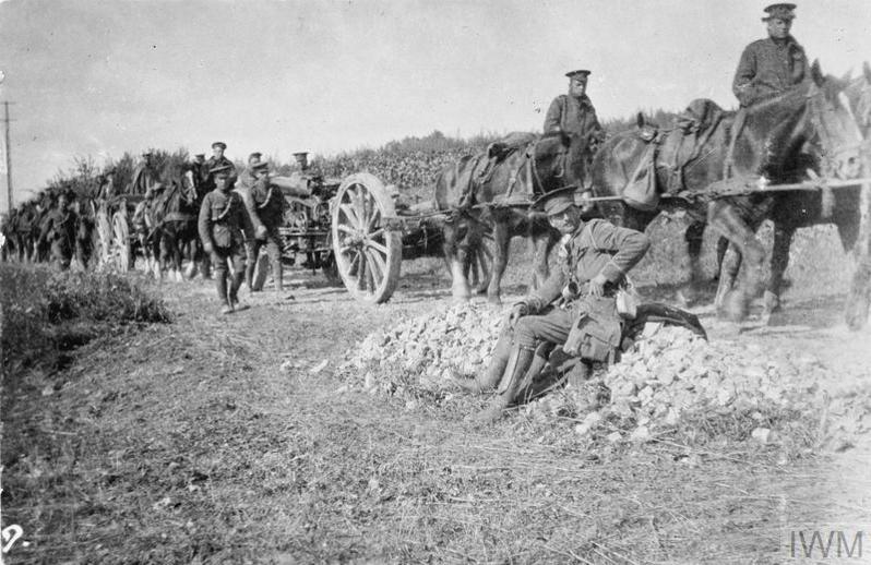 A column of Britihs soldiers, led by a horse-drawn field gun, on the move along a damaged French Road in 1914.