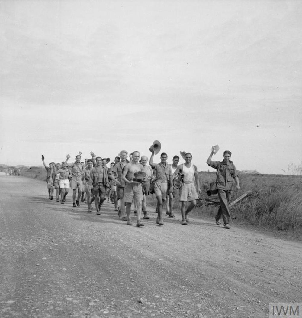 A group of recently released British prisoners of war march toward an airfield in Thailand ready for repatriation.