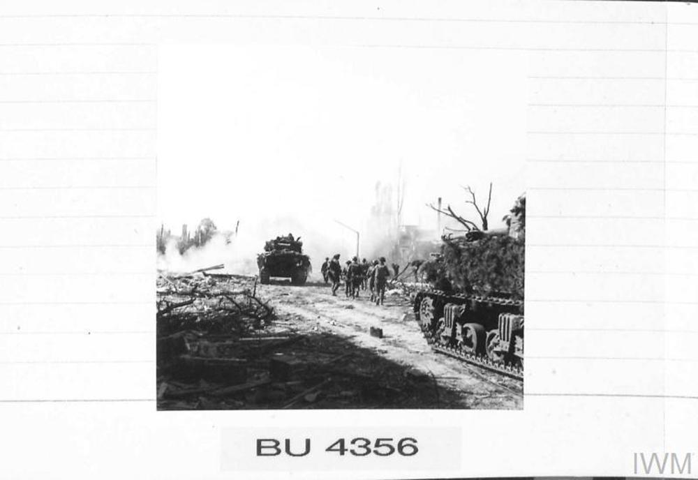 British tanks and infantry move into Bremen. A smoky fire burns in the rubble of smashed buildings.