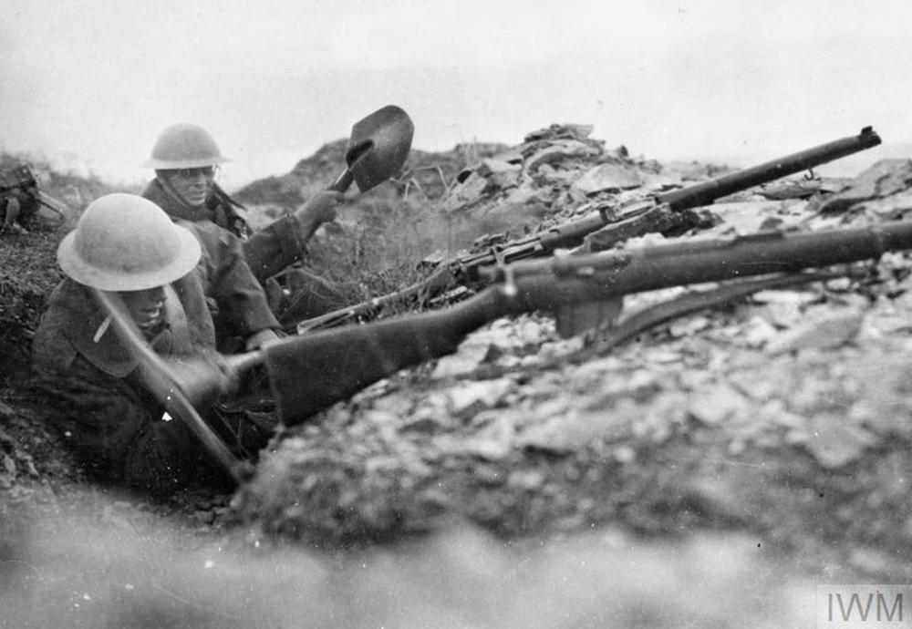 British soldiers digging in rocky ground to deepen a trench during the Battle of Lake Doiran. They have rest their rifles on the edge of the trench.