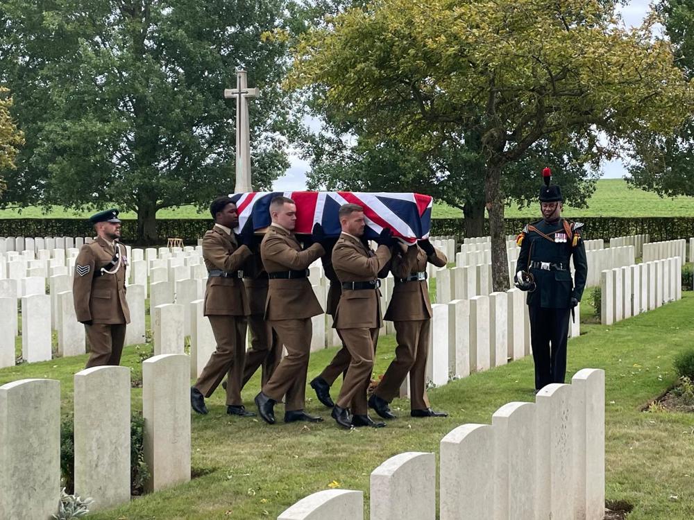 British soldier carrying a Union Hack Draped coffin in a CWGC cemetery.