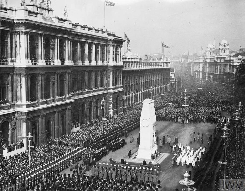 Armistice Day Parade in Whitehall pass the Cenotaph in London in November 1931. The street is lined with crowds and guards while various digniatries stand cermeonially around the Cenotaph.
