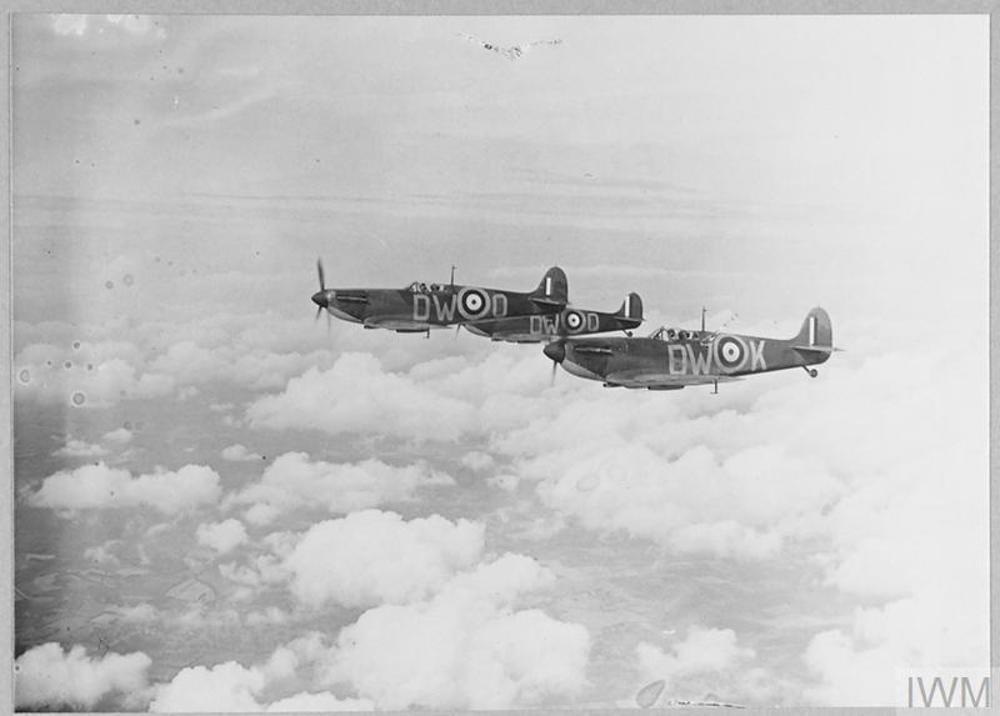 Thee Spitefire fighter planes flying in formation high above the clouds.