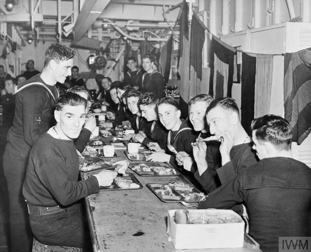 Sailors eating special christmas dinners aboard an escort vessel during the Second World War.