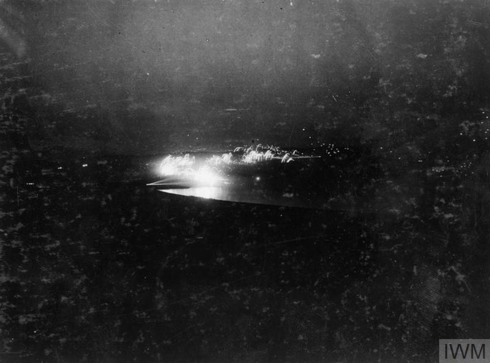 Muzzle flashes and blasts from British artillery highlighted against a dark night sky at Lake Doiran.