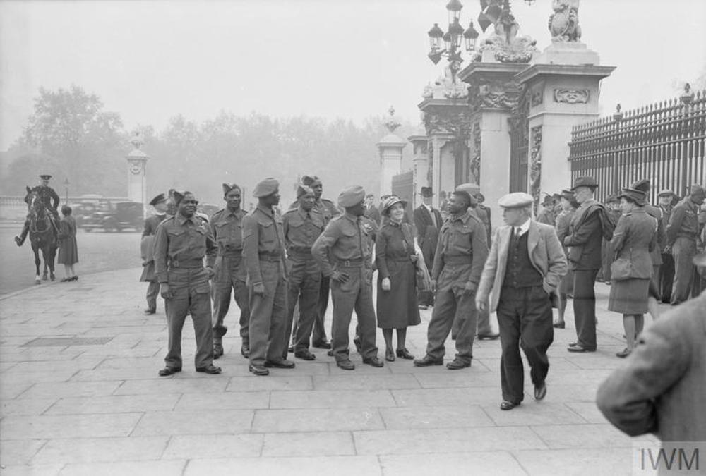 A group of black Caribbean servicemen of the British Army mixing with crowds outside the gates of Buckingham Palace.
