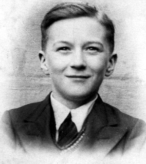 Reggie Earnshaw as a school boy wearing blazer, tie, and knitted vest over a collared shirt.