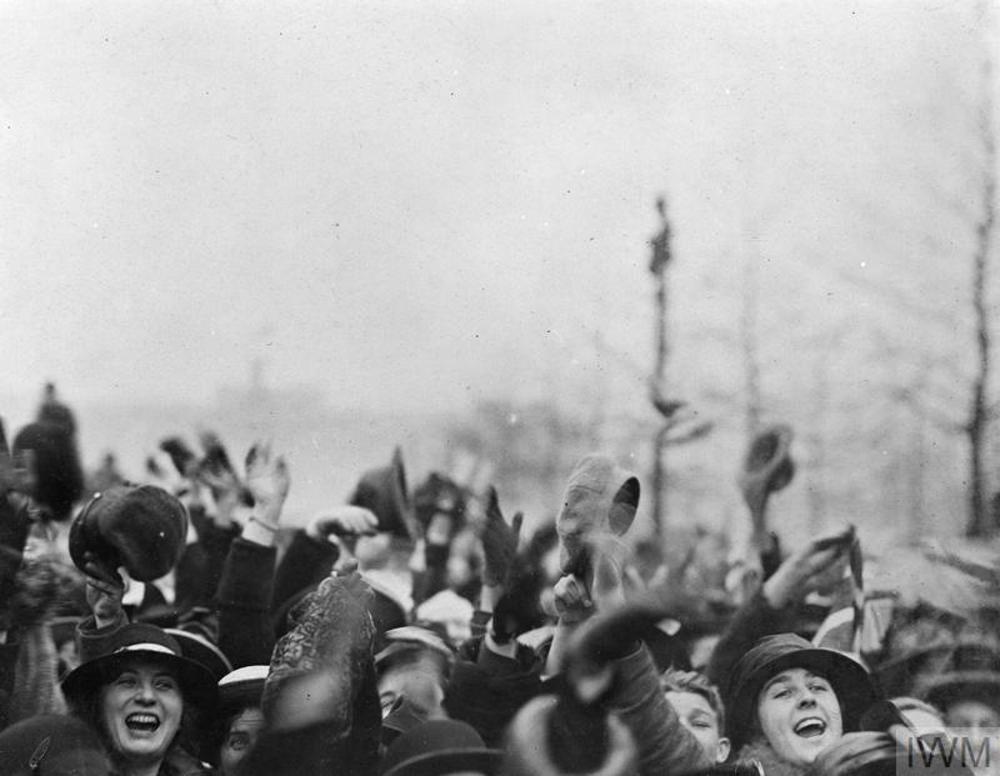 Crowds celebrate the Armistice in London, November 1918, by waving their hats in the air and cheering.