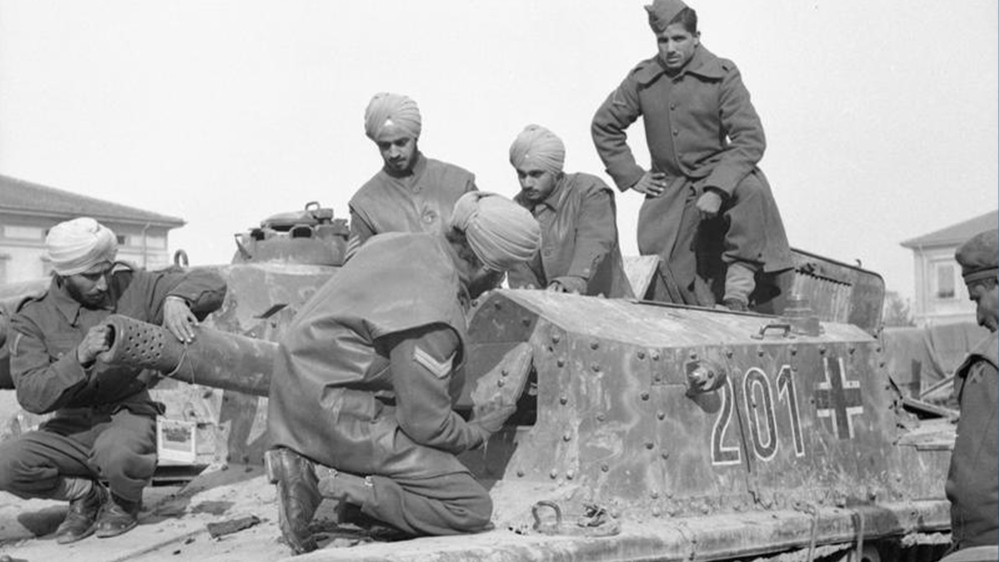 Indian Army soldiers inspecting a German self-propelled gun in Italy. Three of five soldiers are clearly Sikhs wearing turbans.