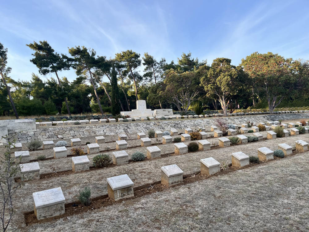 Rows of low white stone war grave markers on a coarse dry lawn in a war cemetery in Gallipoli.