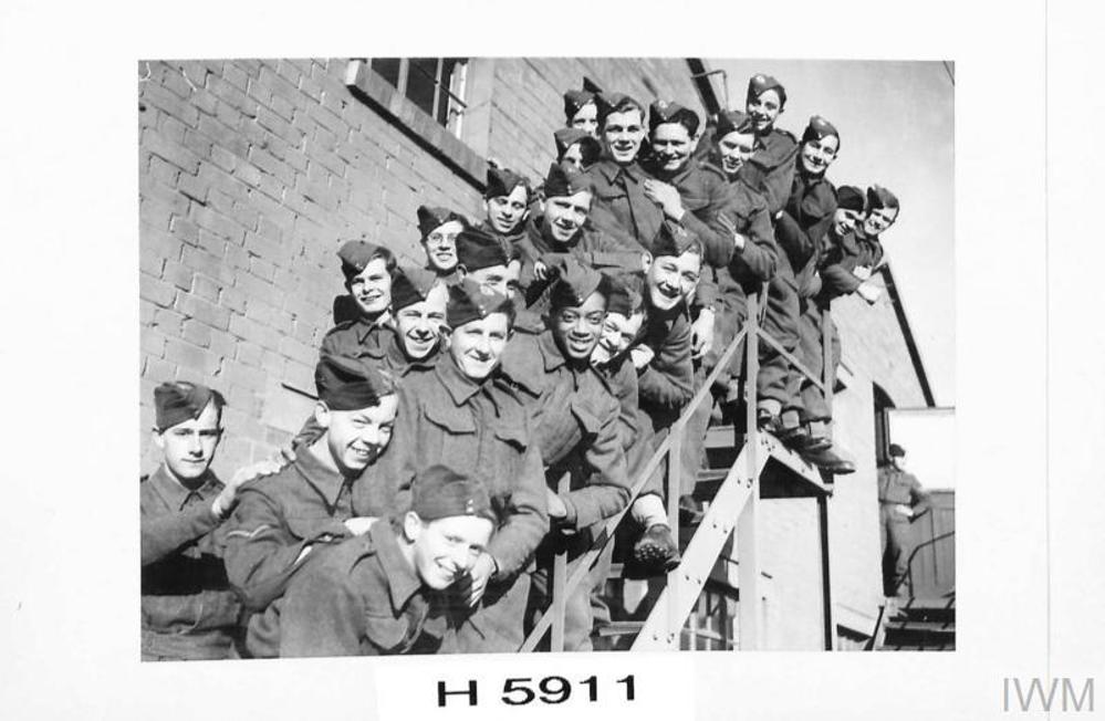 A group of soldiers from the Young Soldiers' battalion posing for the camera on a staircase attached to a red brick building somewhere in a British military barracks during the Second World War.